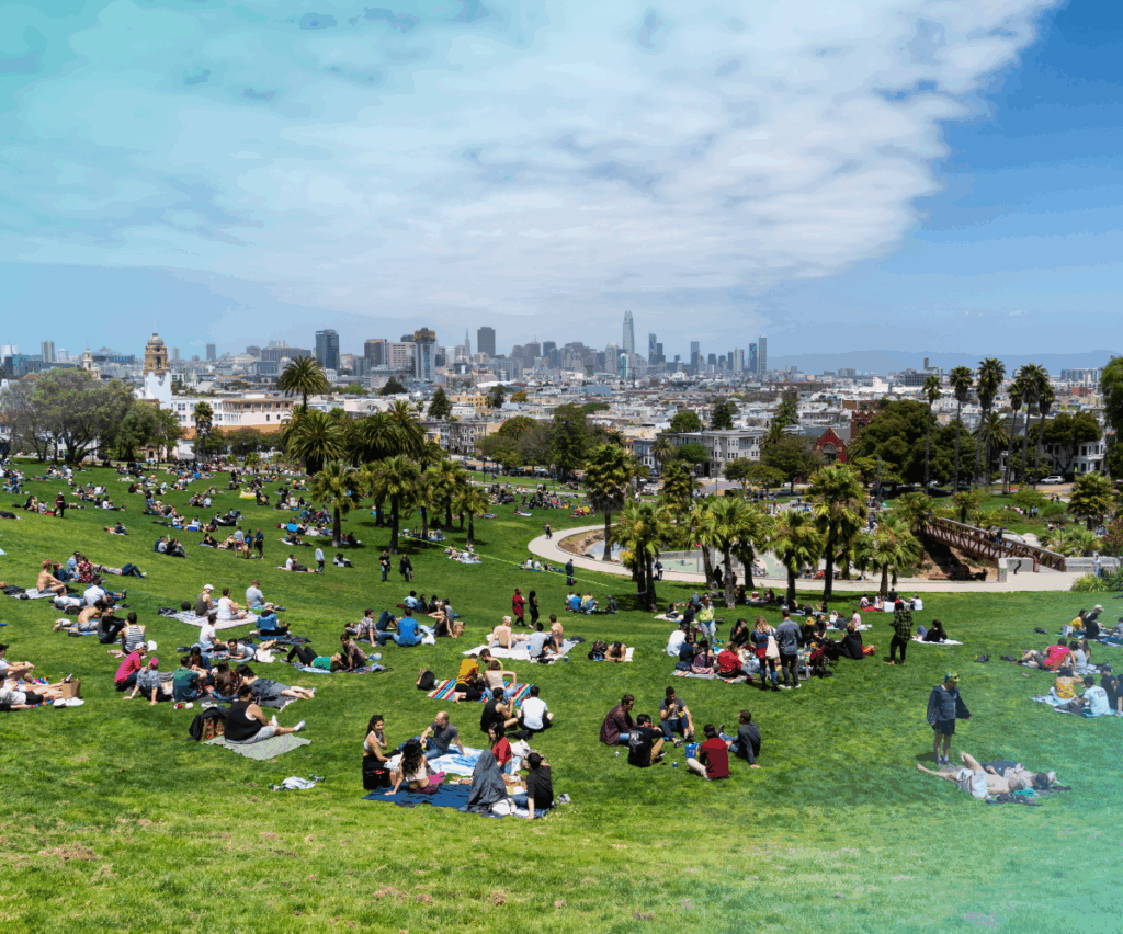 People relaxing on the grass at Dolores Park in San Francisco with city skyline in the background