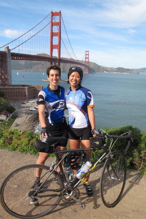 Jenni and Lisa standing with a bicycle in front of the San Francisco Bridge